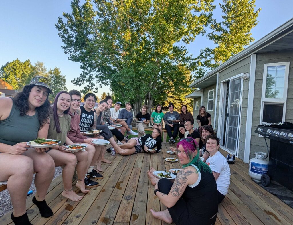 A group picture of BAD All-Stars sitting on a porch in Montana with plates on their laps.