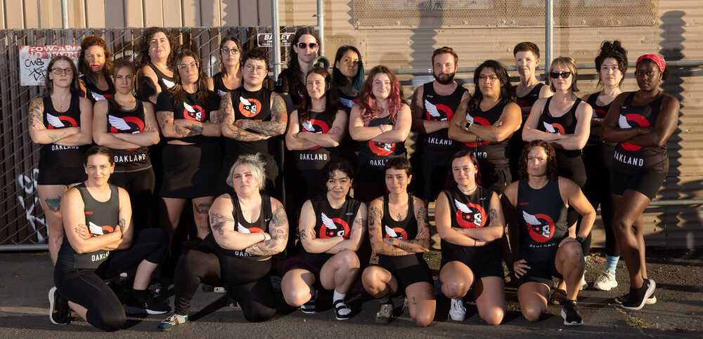 Group photo of Oakland Outlaws players with arms crossed standing in front of a corrugated metal wall.